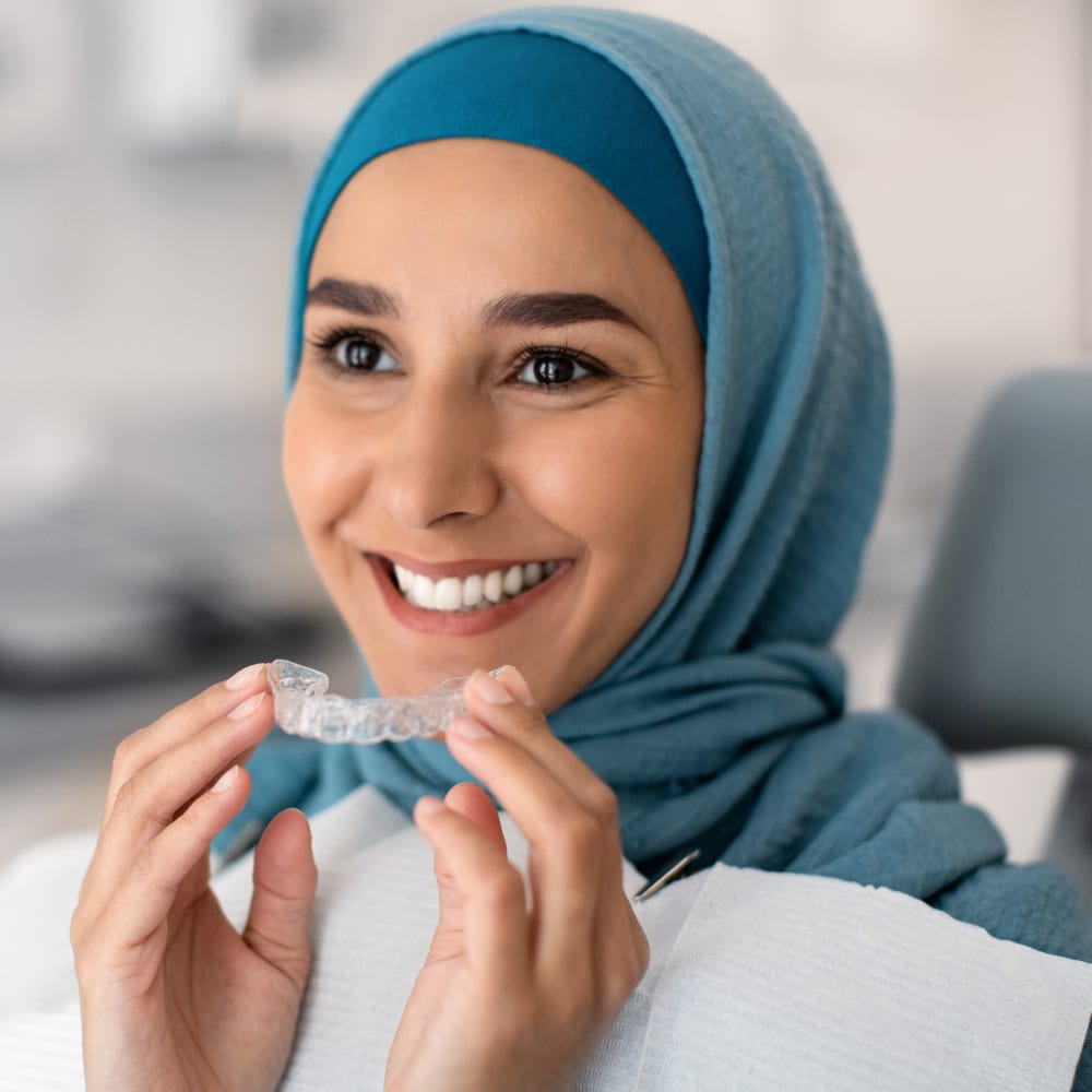 Closeup portrait of smiling woman about to put in upper clear aligner.