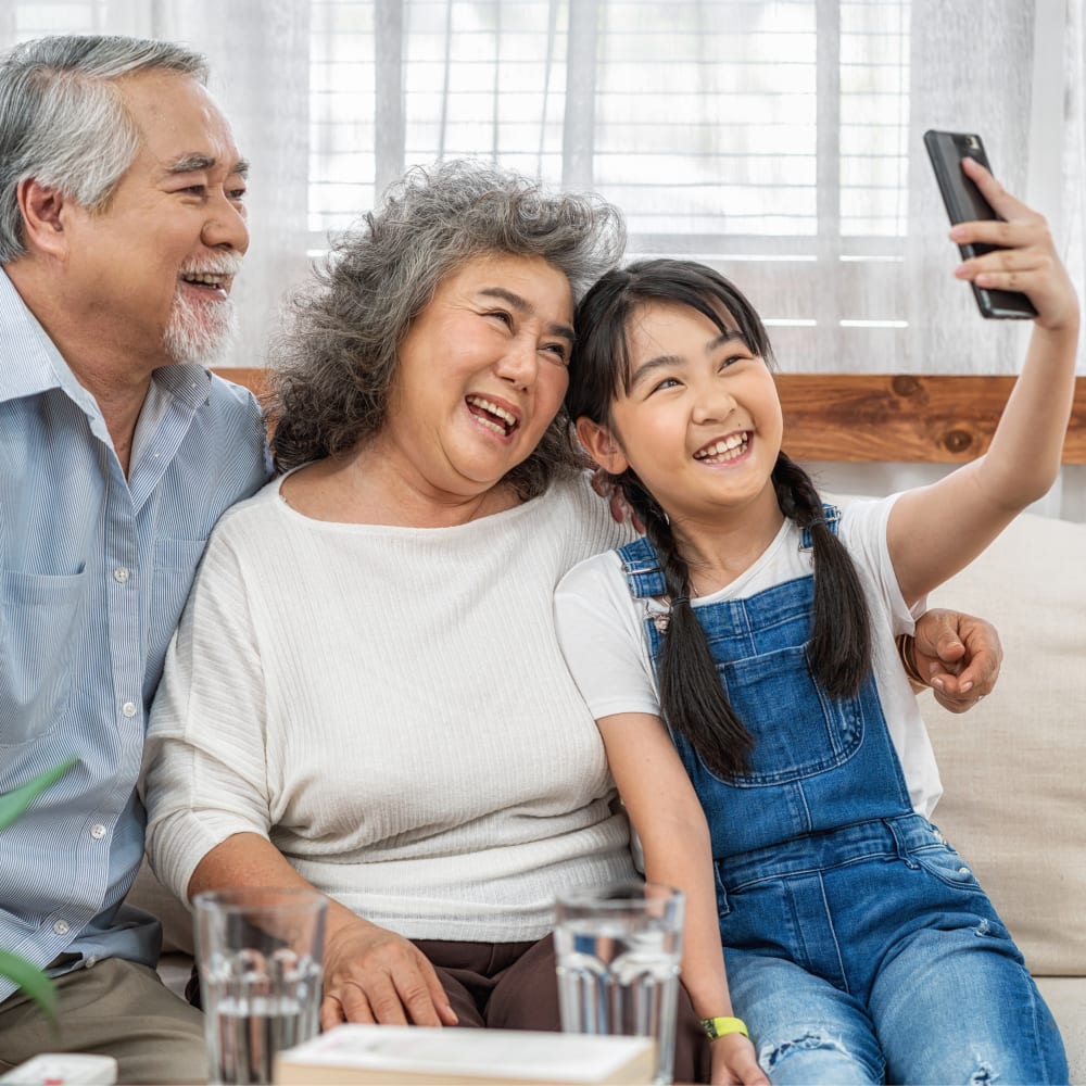 Young girl taking smiling selfie with her grandparents.