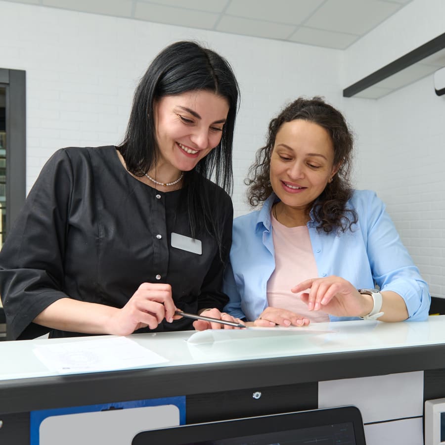 A woman and a receptionist fill out paperwork.