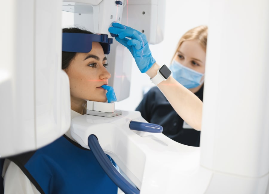 A patient sits with their face in a 3D CBCT machine.