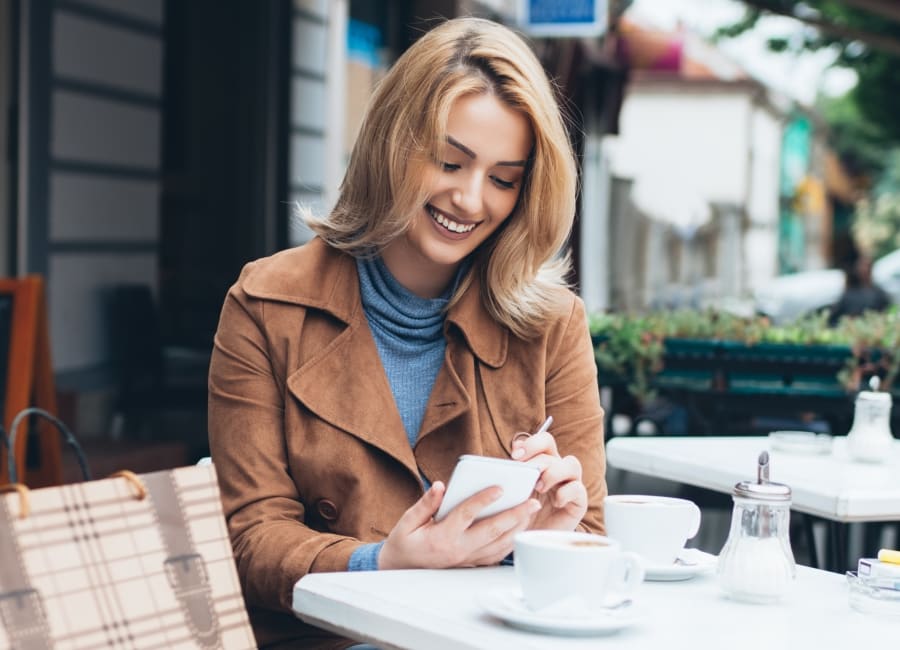 Woman at outdoor cafe looking at cell phone.