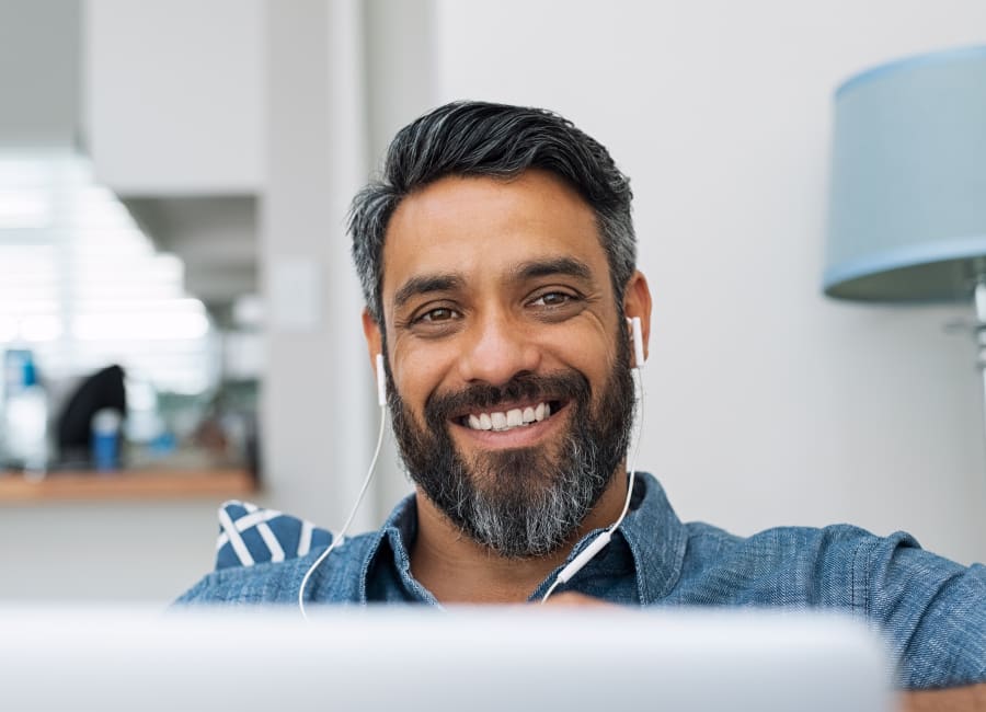 Man wearing earpods, sitting in front of his laptop.