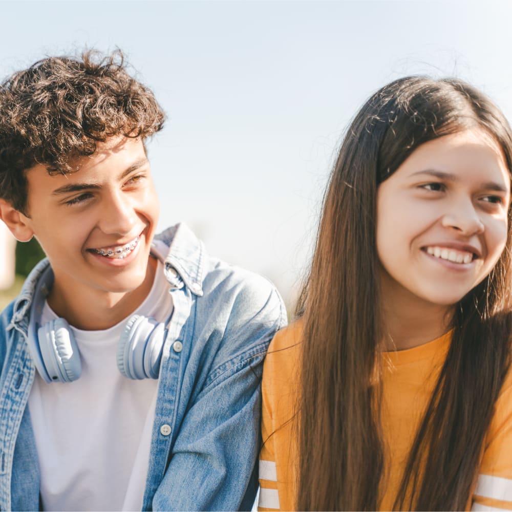 Two teenagers smiling at someone out of the shot to their left.